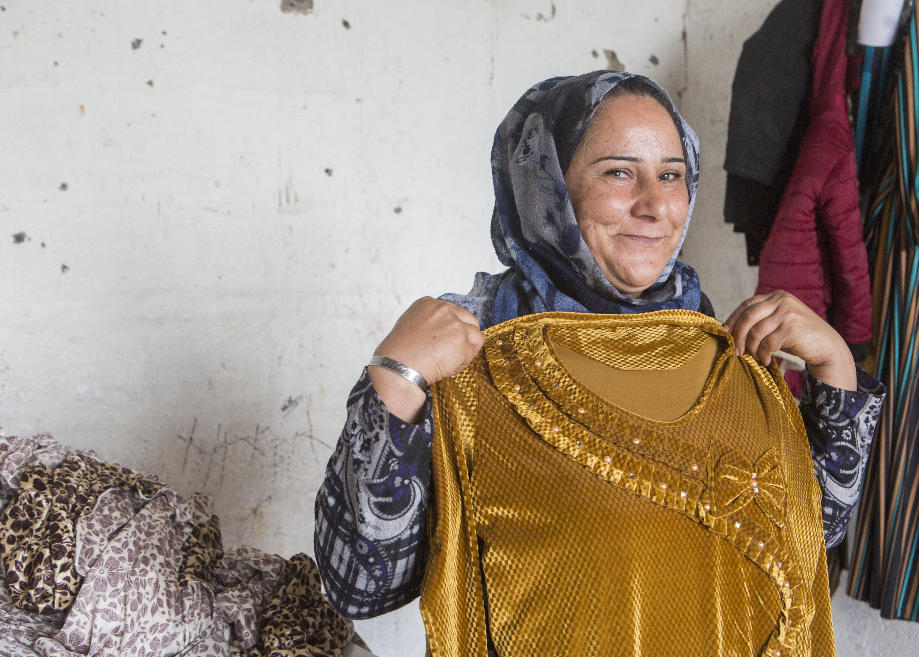 Shireen holding up a dress she made using the skills she learnt during the Stronger Women, Stronger Nations programme. Photo: Alison Baskerville.