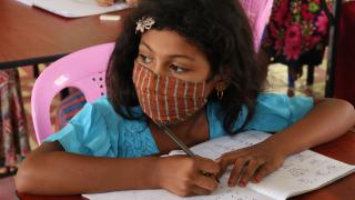 Girl writing in exercise book at school