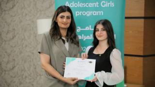 Linda handing certificates at the Adolescent Girls Programme graduation ceremony, Iraq, 2025. Photo: Women for Women International