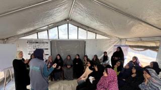 Group of women sat listening to two teachers hosting an awareness session