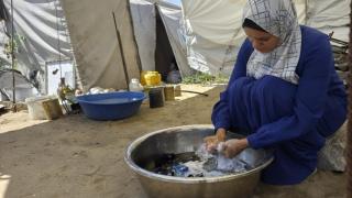 Hanaa washing clothes outside in a big metal bowl