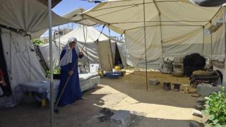 Hanaa sweeping her compound under a tent
