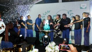 Group of people standing around a large cake at an anniversary celebration