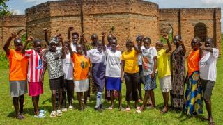 Group of girls posing together with one arm above their heads in fists