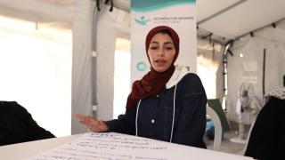 Woman speaking while sat at a table with notes on it