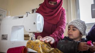 Raja Jidan Ali practices sewing as her daughter Tarq looks on. Photo: Emily Kinsey