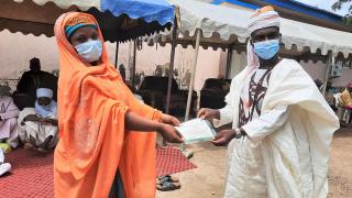 A new graduate receives her certificate at a COVID compliant graduation ceremony in northern Nigeria. Photo: Women for Women International