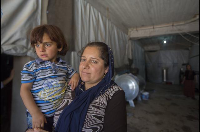 A refugee holds her child in a tent in the Khanke refugee camp in Iraq. Photo: Alison Baskerville
